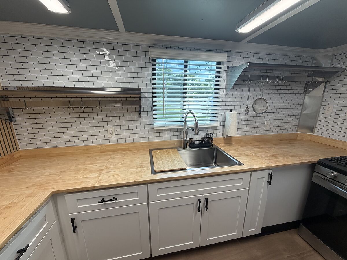 Butcher block counters, deep stainless sink and open shelving inside the trailer